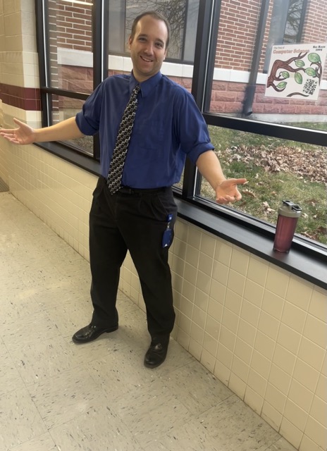 Mr. Hansell posing in the 100 wing hallway.