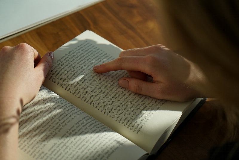 Woman reads a book on a wooden desk. Original public domain image from Wikimedia Commons